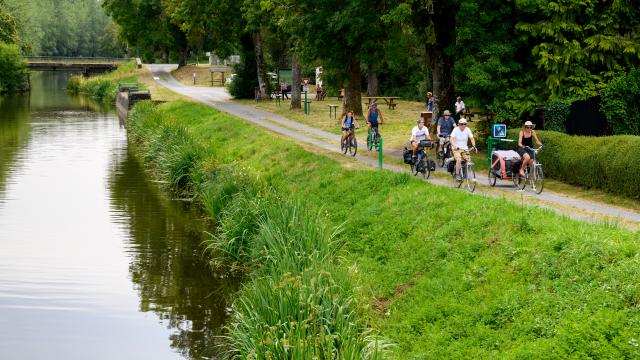 Cyclotouristes roulant sur le chemin de halage le long du Canal de Nantes à Brest, à la jonction avec les Voies Vertes et la Vélodyssée