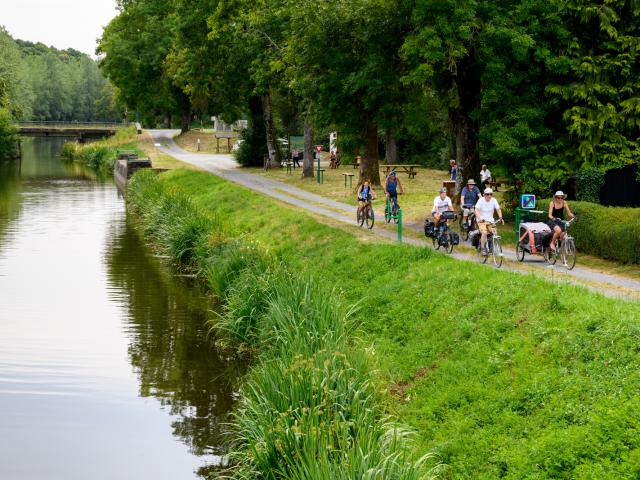 Cyclotouristes roulant sur le chemin de halage le long du Canal de Nantes à Brest, à la jonction avec les Voies Vertes et la Vélodyssée